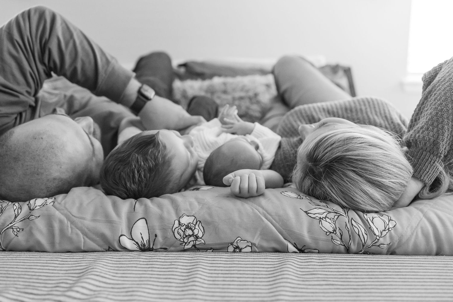 Black and white image of sleeping baby on textured bedding.
