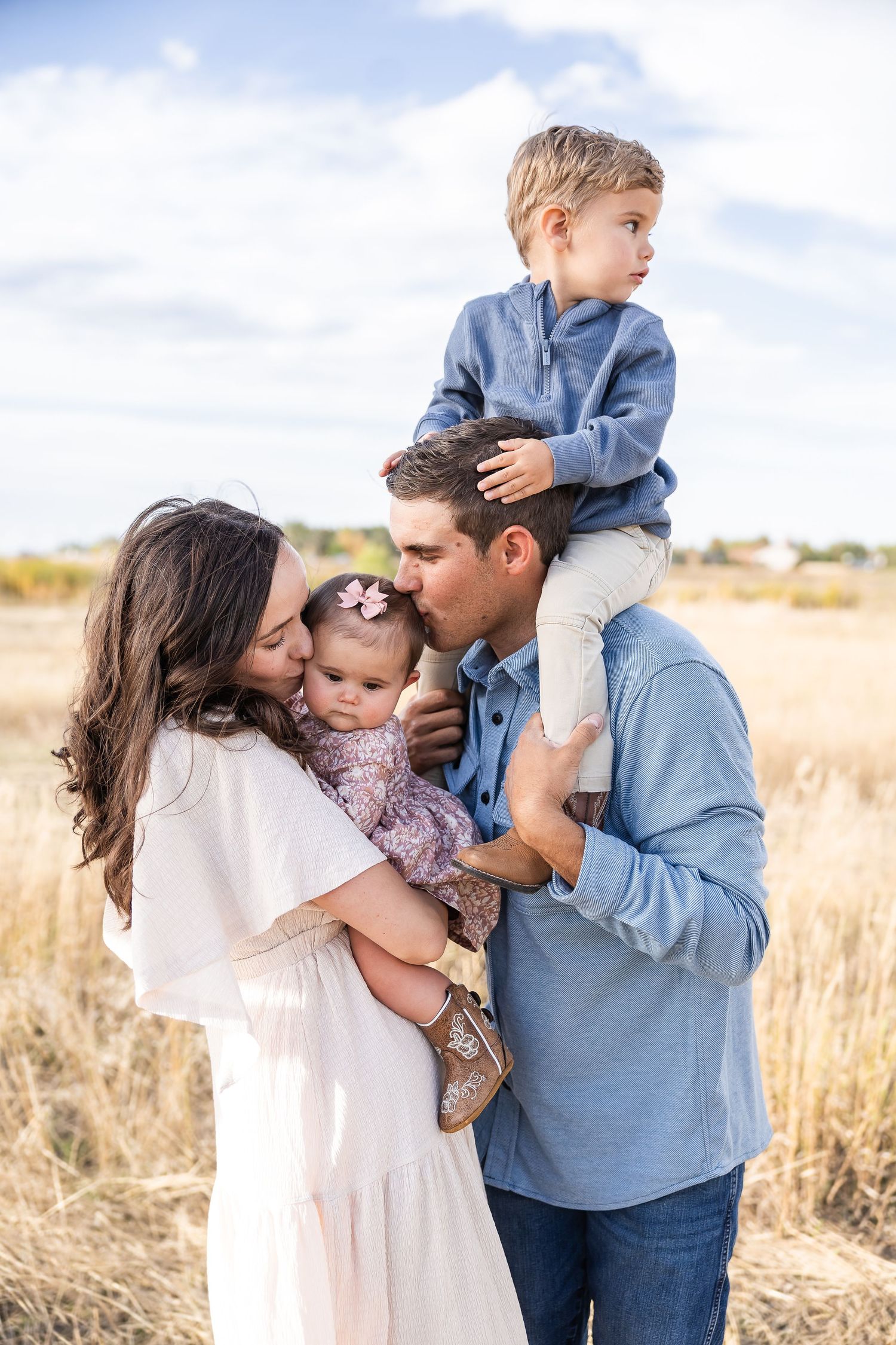 Intimate family moment captured in a sunlit field with tall grass.