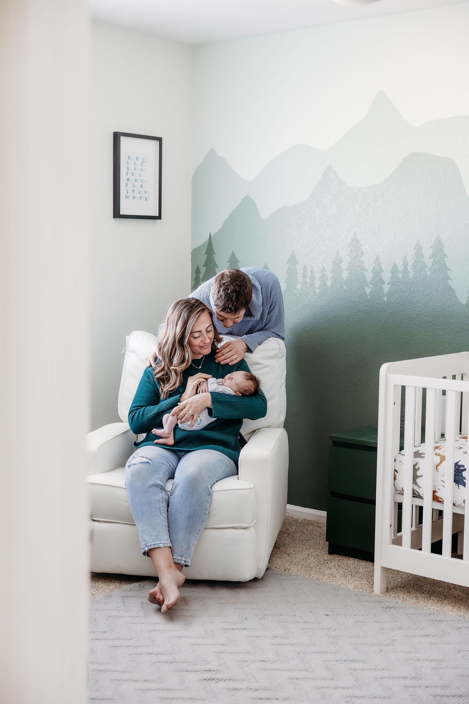 Nursery room with mountain mural wall art and white rocking chair.