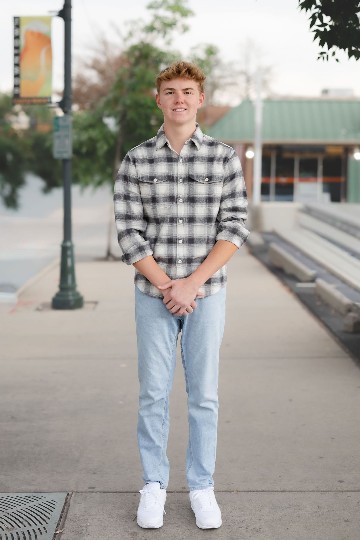 Casual portrait session on a sidewalk featuring plaid shirt and light denim jeans.