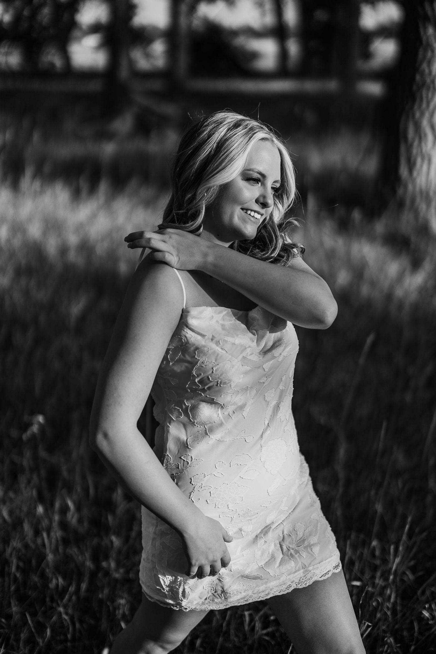 Person in white lace top laughing joyfully in grassy field.