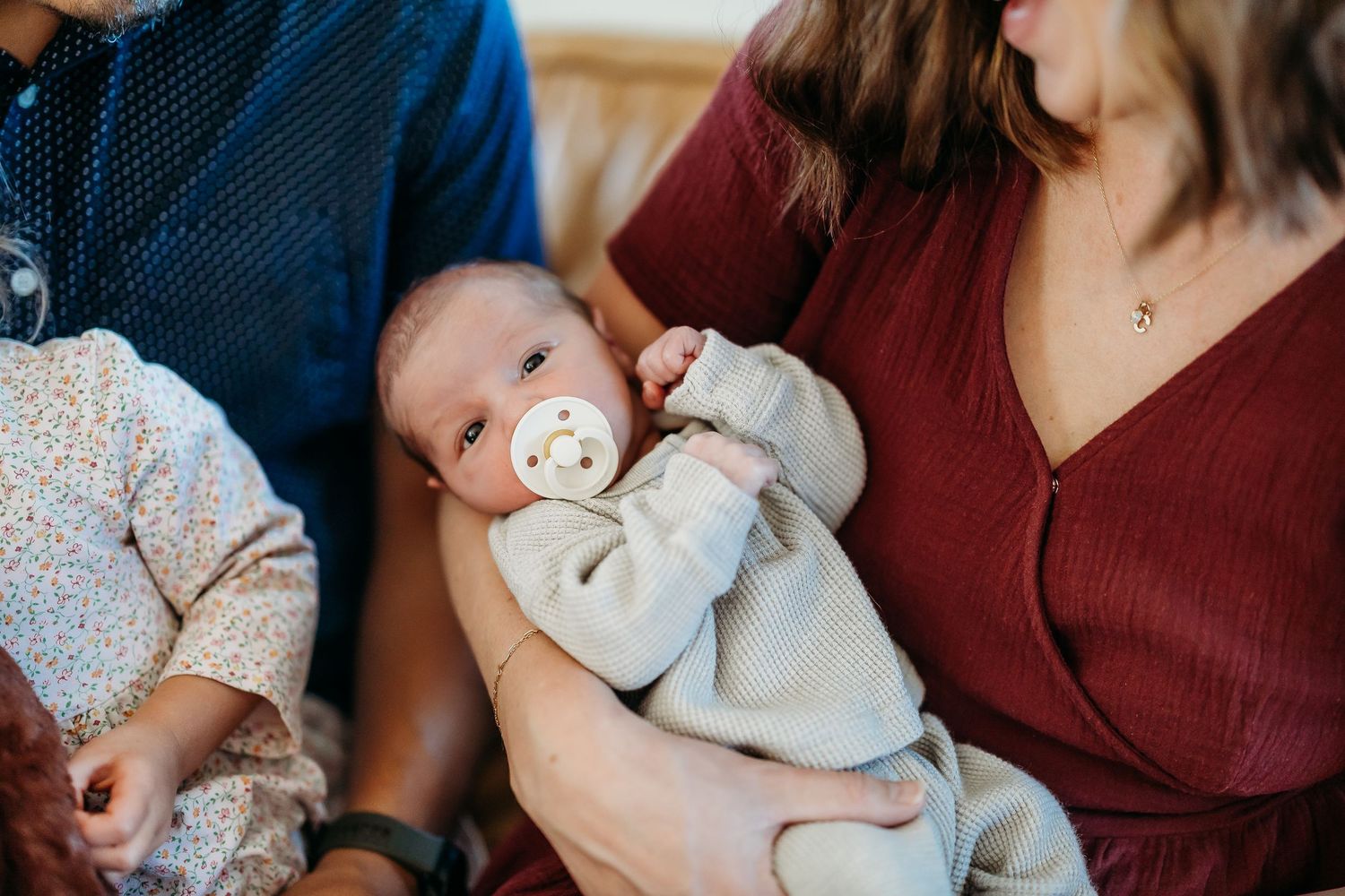 Baby in burgundy colored nursery setting with soft lighting.
