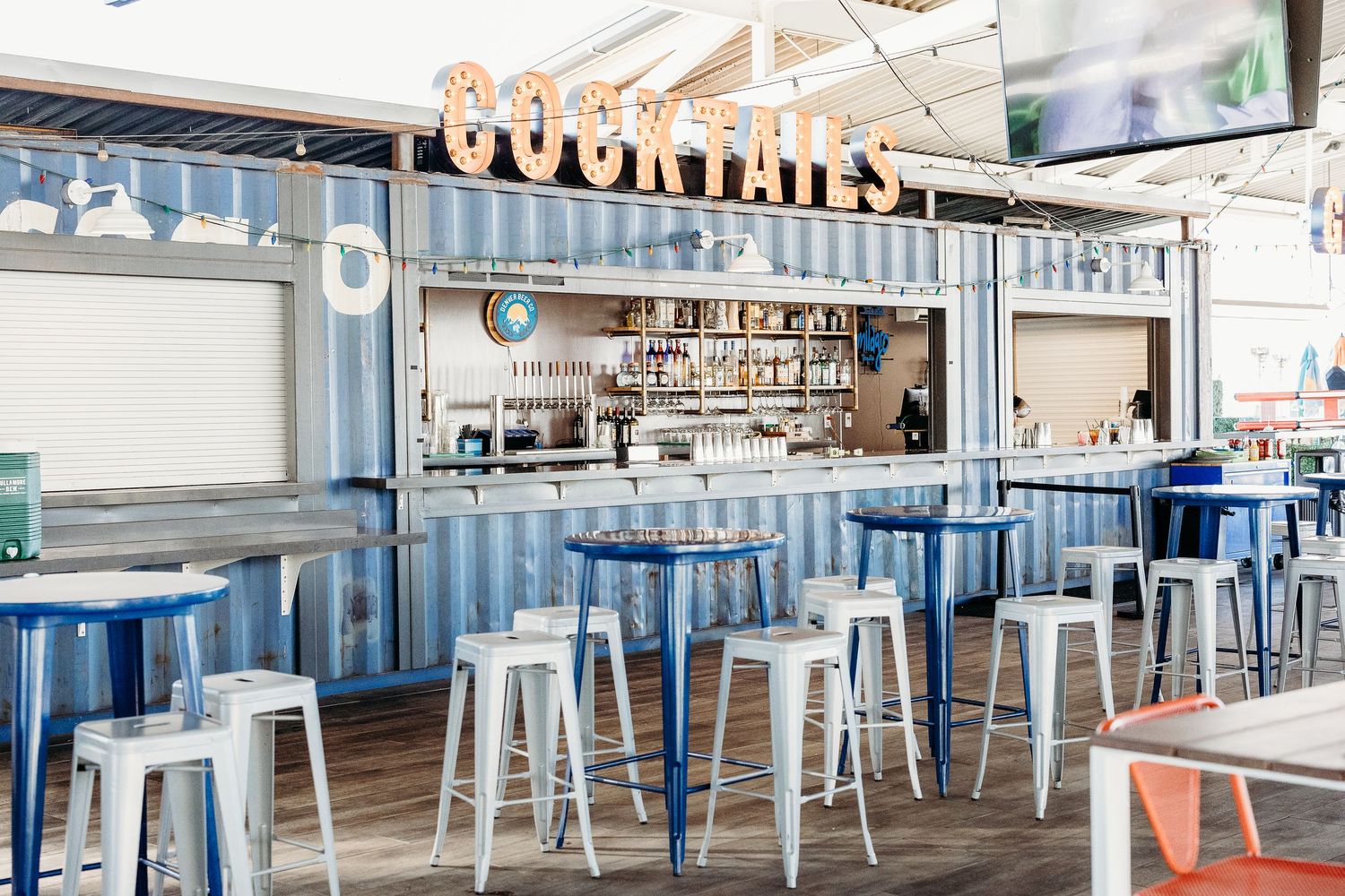 Modern coastal restaurant interior with blue accents and metal bar stools.