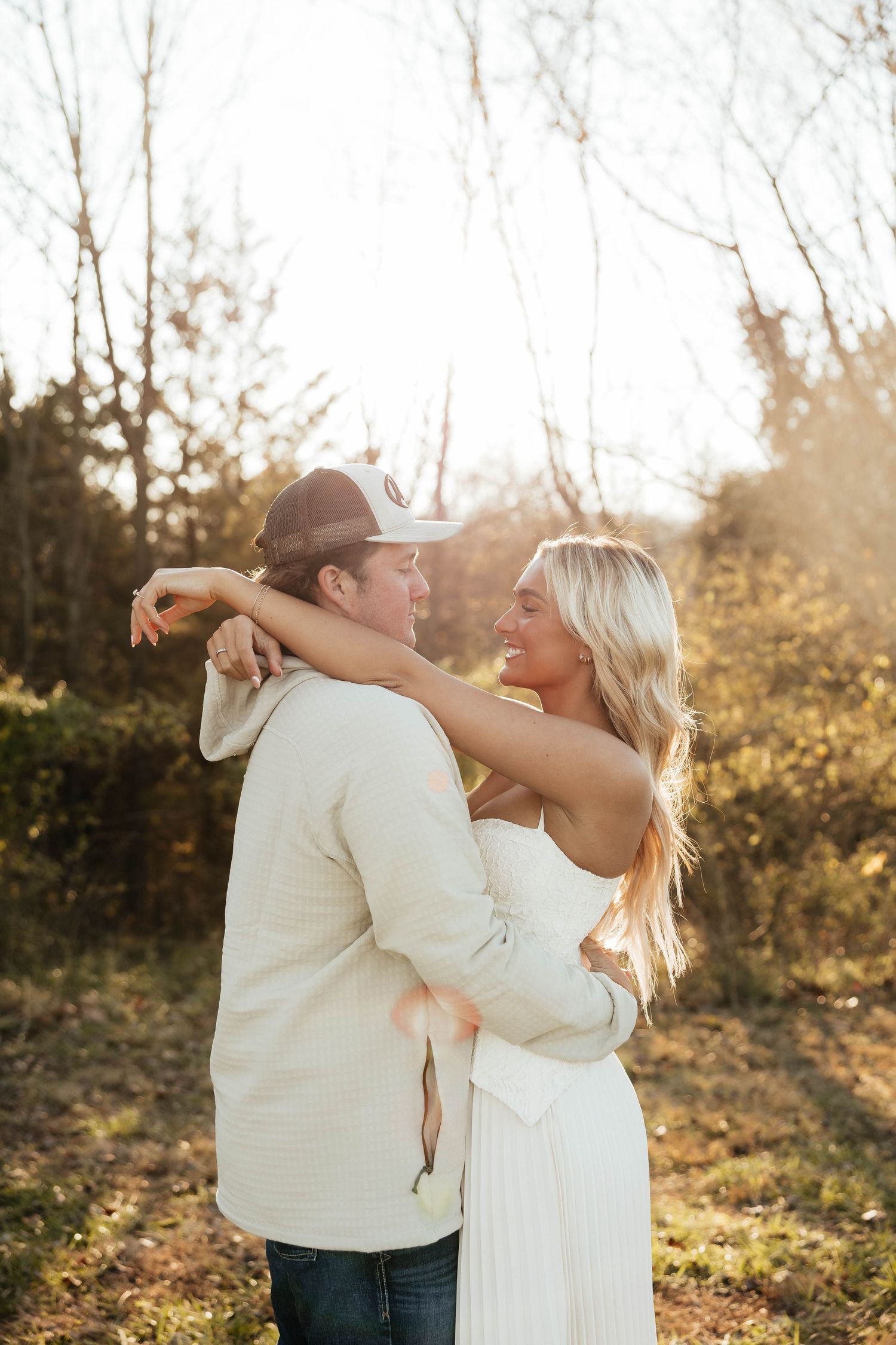 Happy couple embracing outdoors in golden sunlight surrounded by autumn trees.