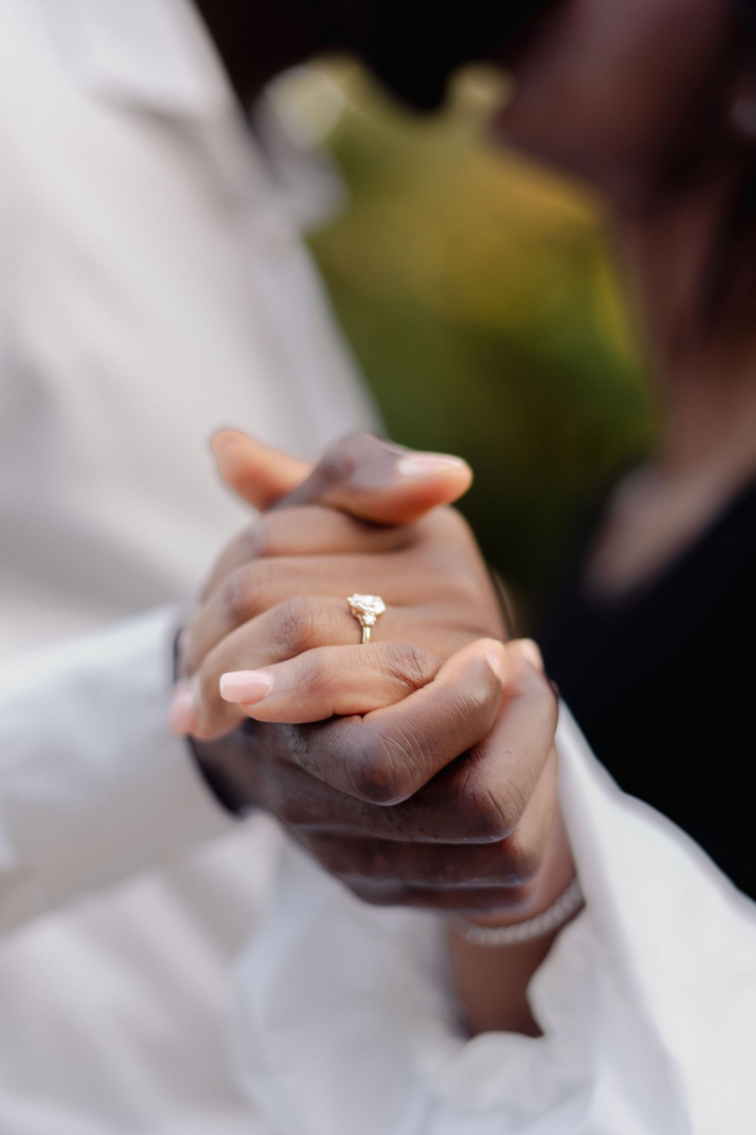 Close-up of hands holding together showing engagement ring.