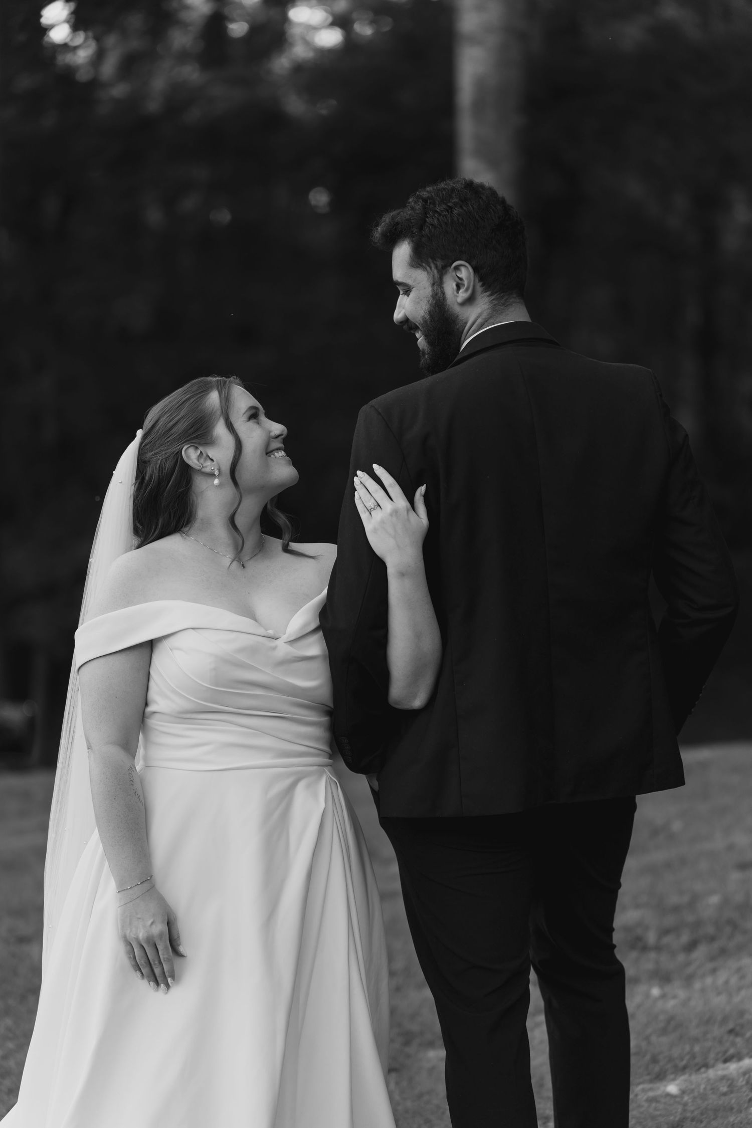 An intimate black and white wedding portrait captures a tender moment between newlyweds.