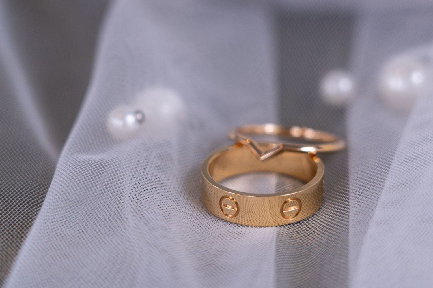Close-up macro shots showing different angles of a delicate gold Cartier Love ring against a soft gray background.