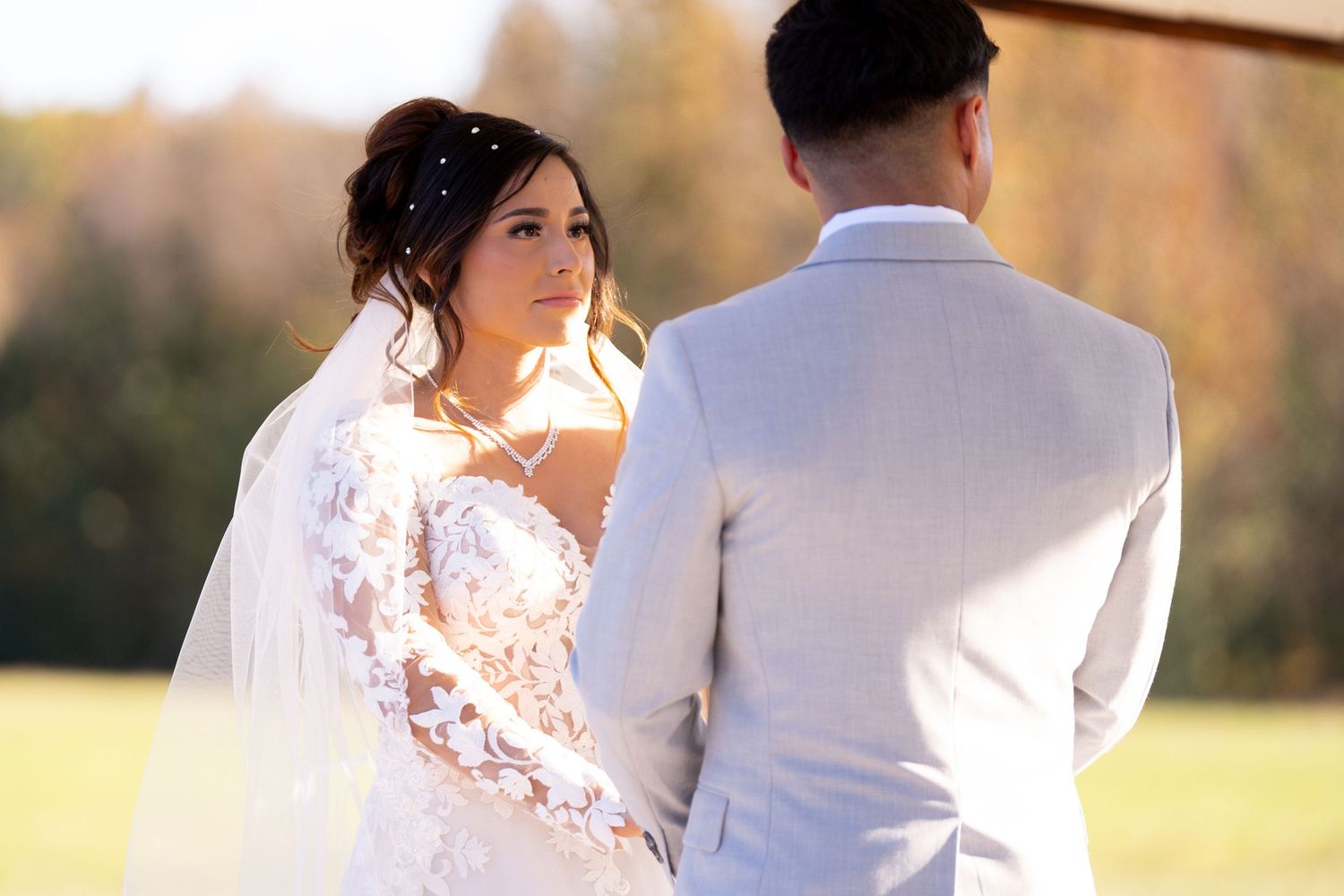 Couple exchanges vows during outdoor sunset wedding ceremony with golden light.