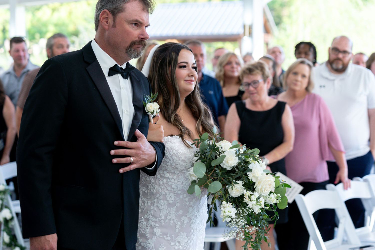 A bride and groom share their first dance at an outdoor wedding reception surrounded by guests.