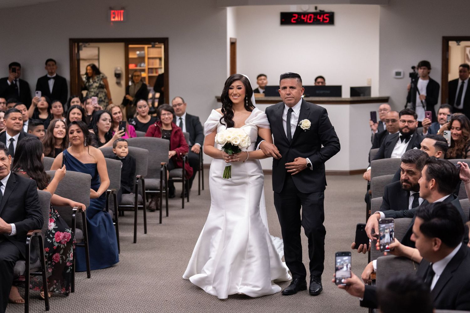 A panoramic view of a wedding reception hall shows guests seated at tables and dancing on the dance floor.