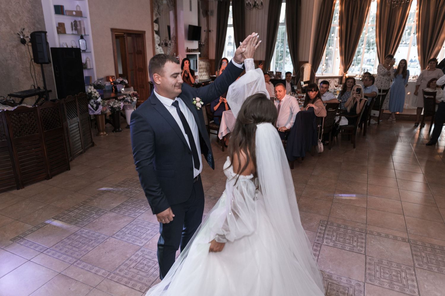 Newlyweds share their first dance together on a rustic wooden dance floor at their wedding reception.