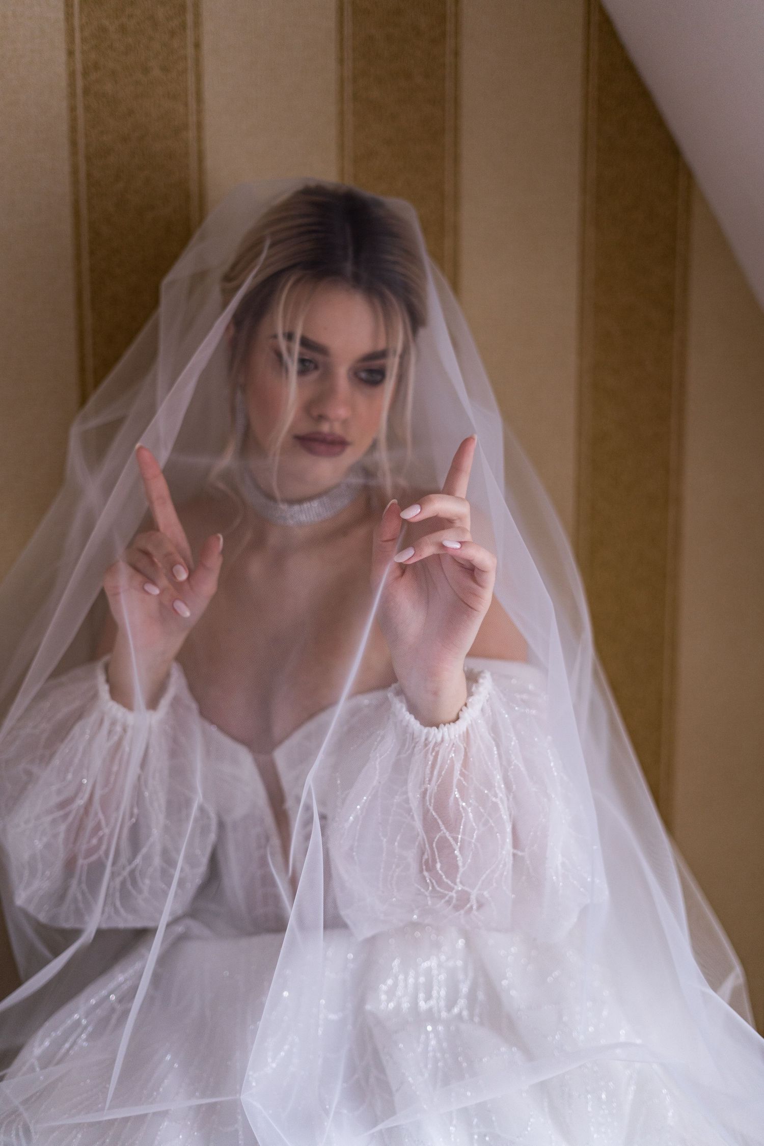 A series of ethereal bridal portraits showing a person in a white wedding dress and veil making playful hand gestures.