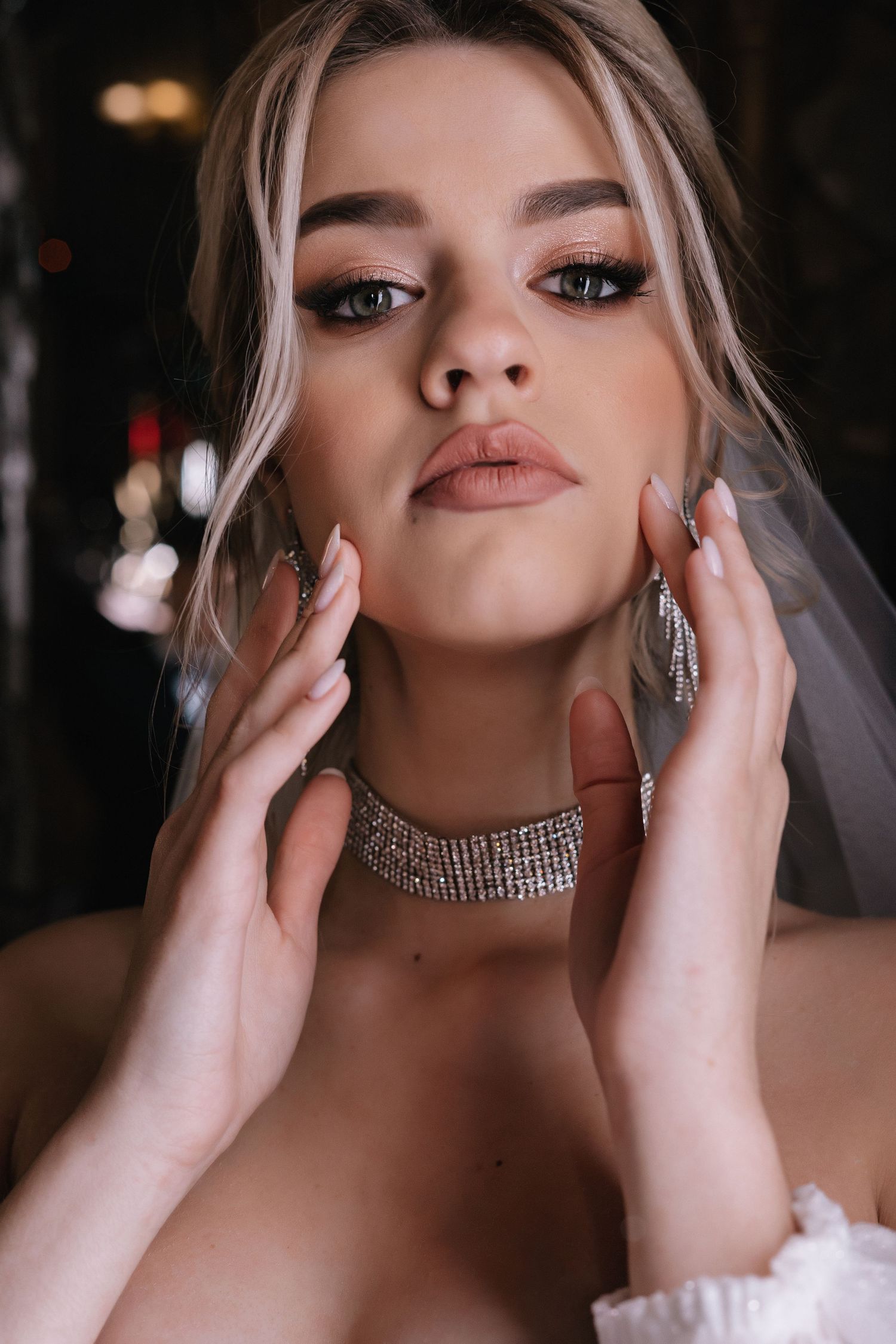 Close-up beauty portrait with glamorous makeup, rhinestone choker and dramatic lighting.