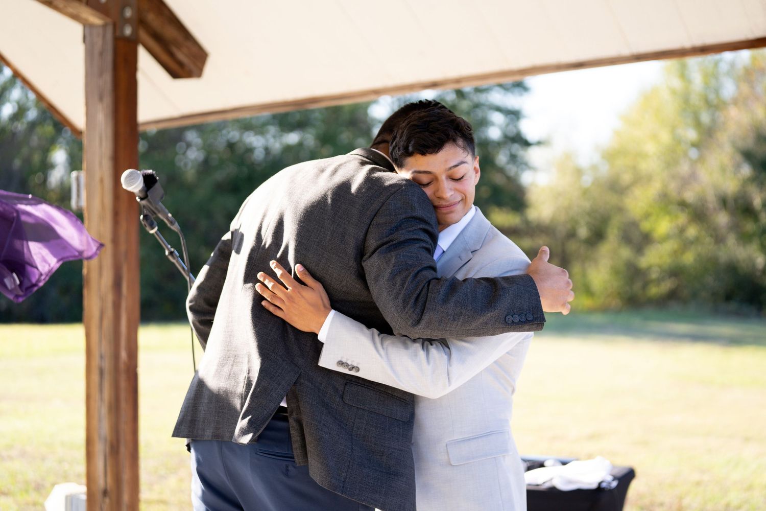 Emotional wedding ceremony moments captured outdoors under wooden pergola.