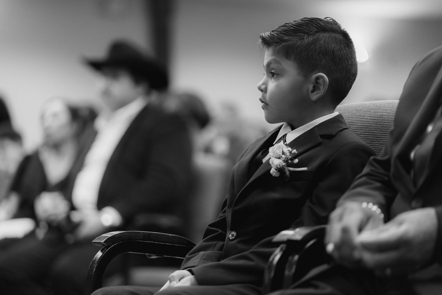 A group of people sit in an audience during an event or performance, shown in black and white.