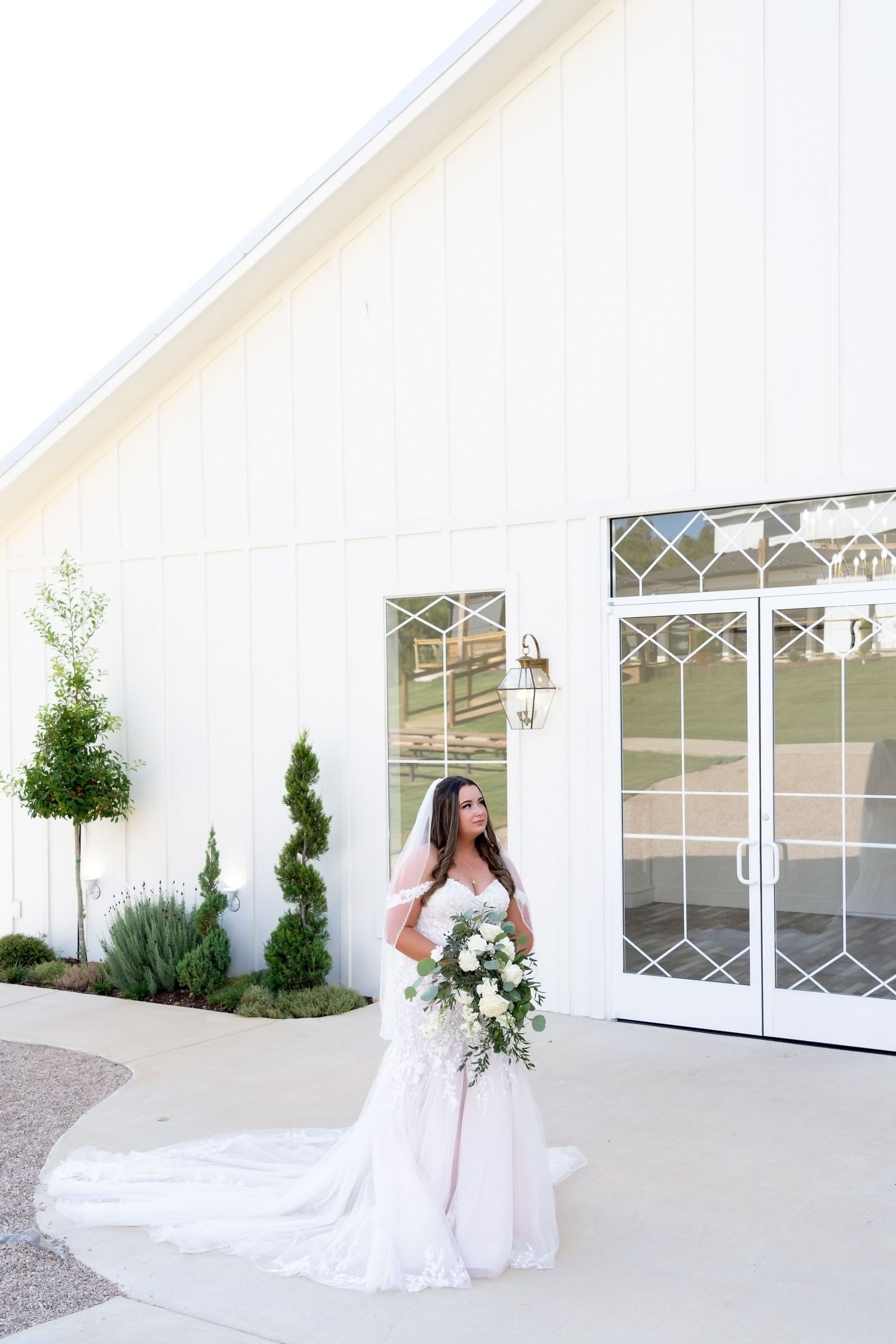A beautiful bridal portrait series showing a flowing white wedding gown against a modern white building exterior.