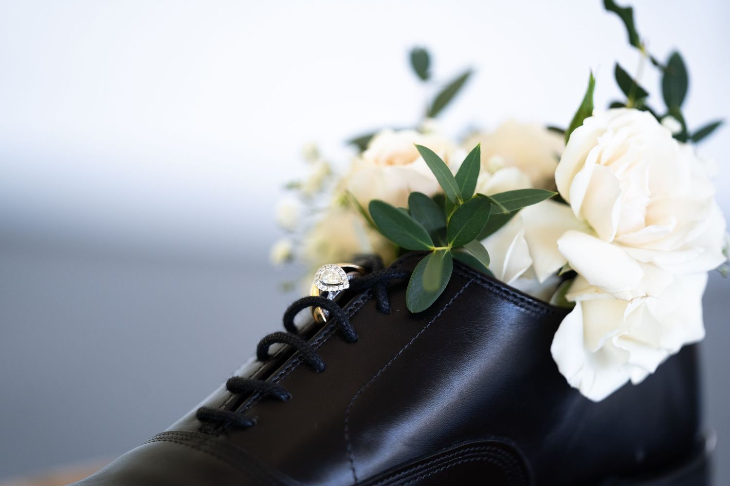 White carnations and black ribbon arranged against a soft blurred background create an elegant contrast.
