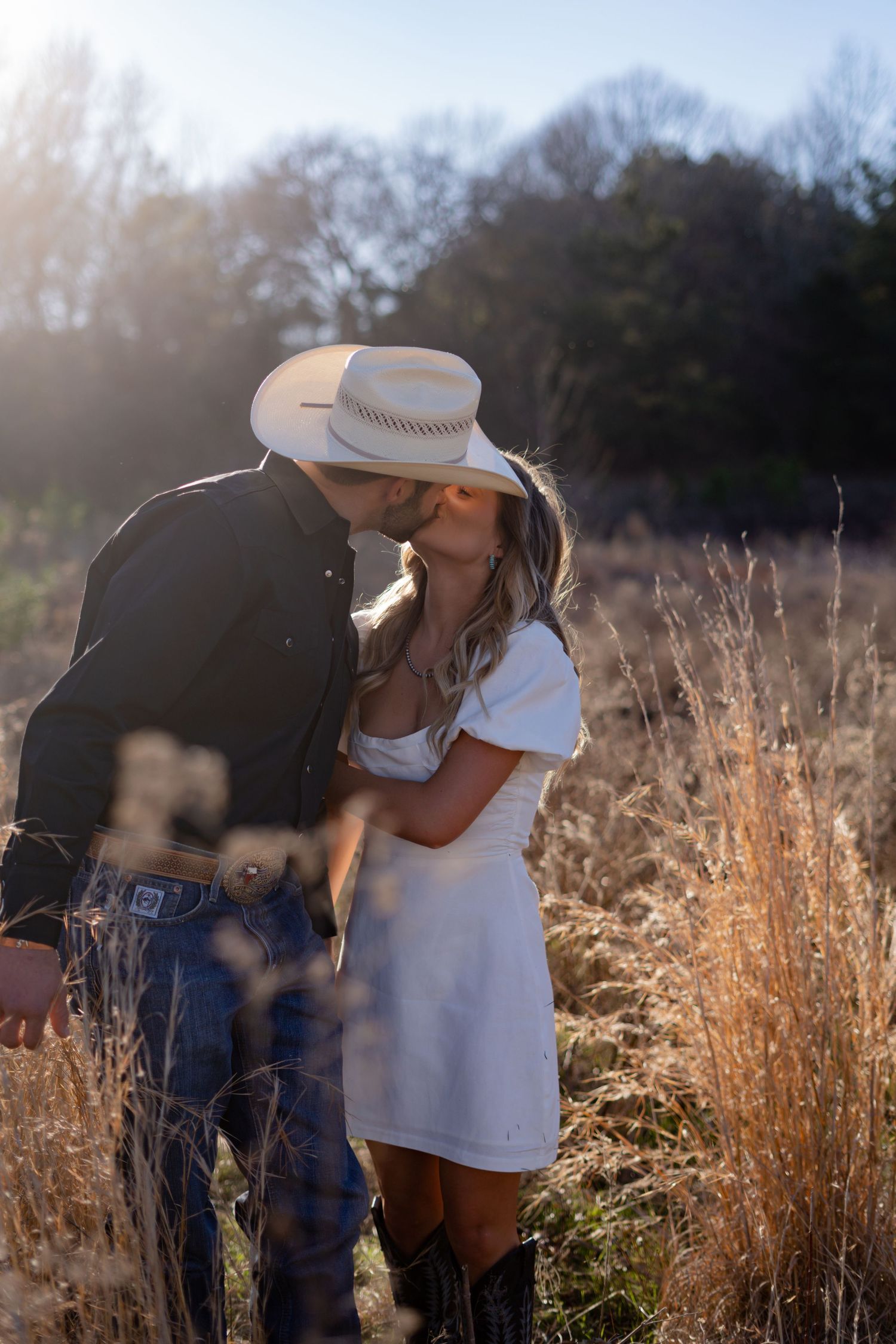 Romantic couple photos in a golden field during sunset with tall grass in the background.