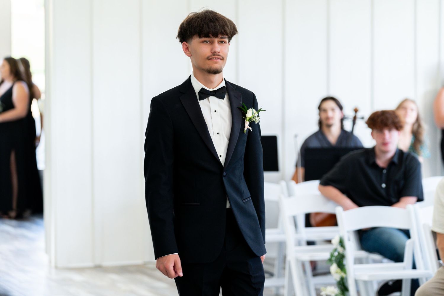 Wedding guests in formal attire gathered at an indoor reception venue.