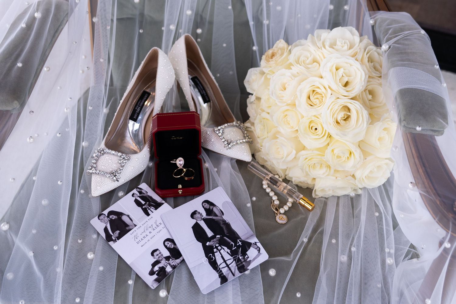 Wedding details featuring white bridal shoes, engagement ring, black and white photos, and a cream rose bouquet on tulle fabric.