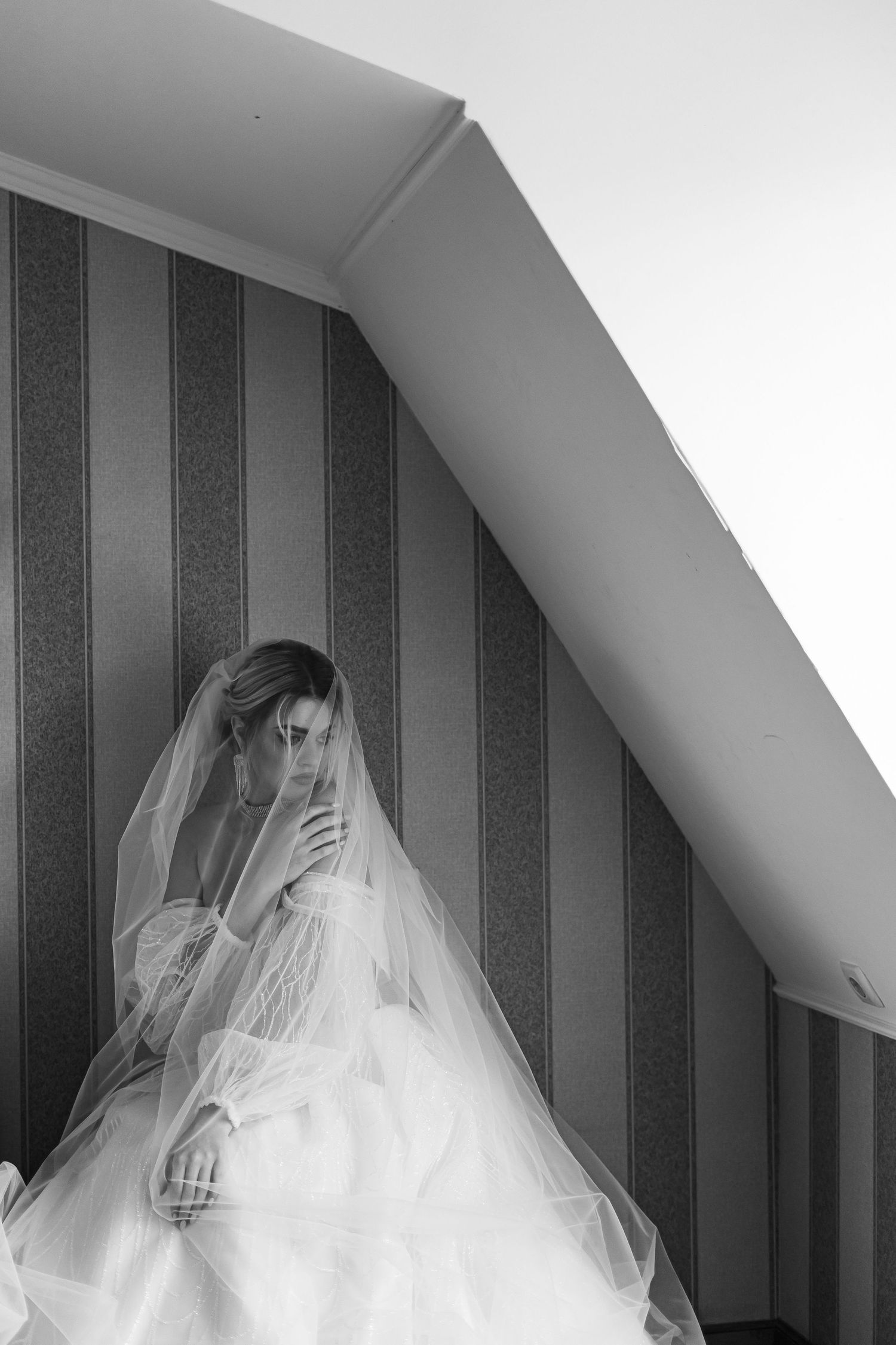 A black and white series of artistic bridal portraits showing a veiled figure against a striped wall background.