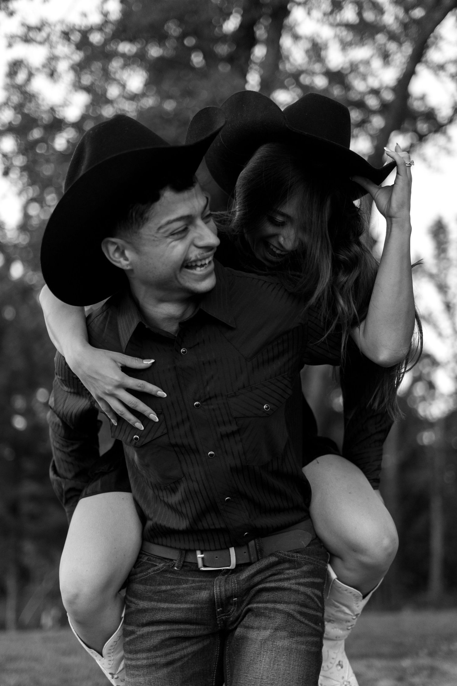 A black and white photo of a playful piggyback ride in a forest setting.