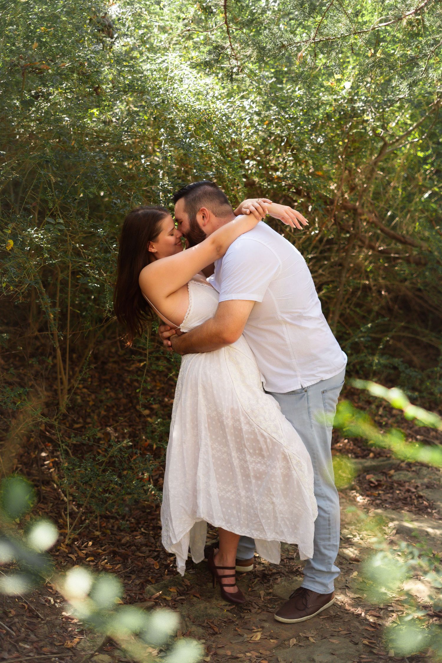 Intimate couple poses together against lush greenery during an outdoor photography session.