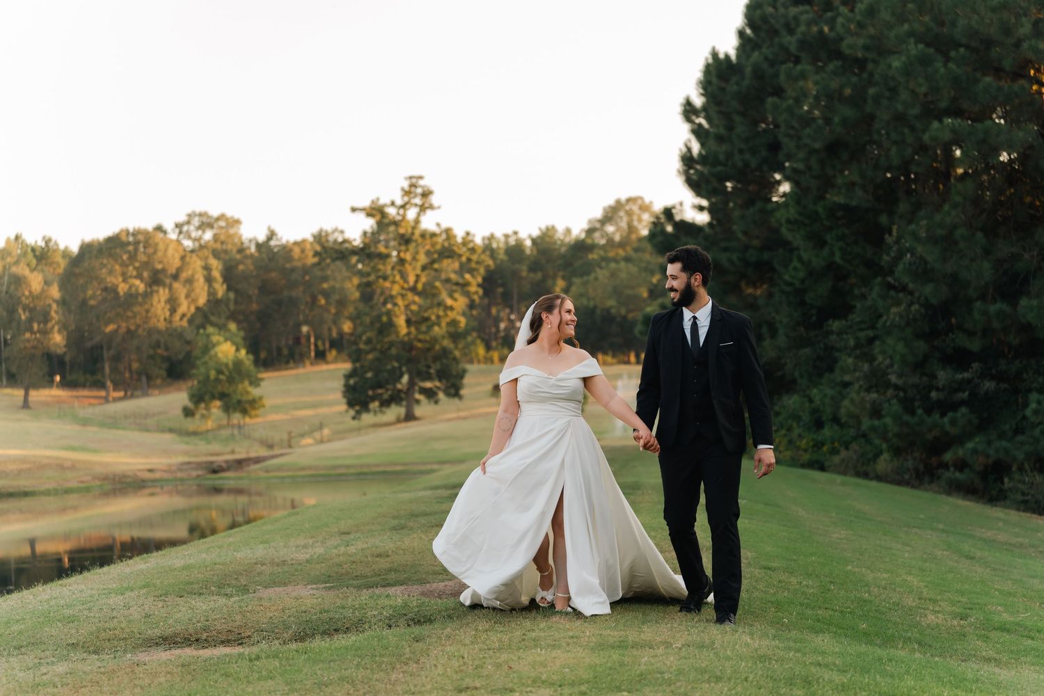 A couple shares a romantic moment on a rolling green golf course at sunset.