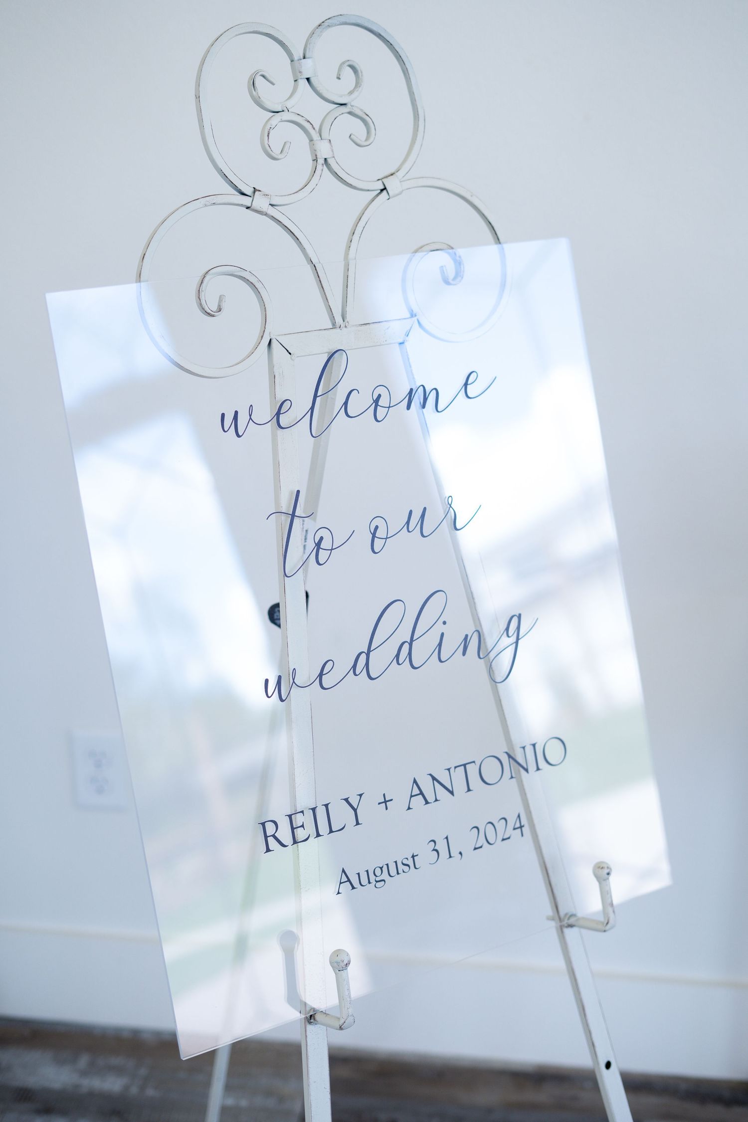Elegant welcome wedding sign with calligraphy text and ornate metal holder displaying names and August 31, 2024 date.