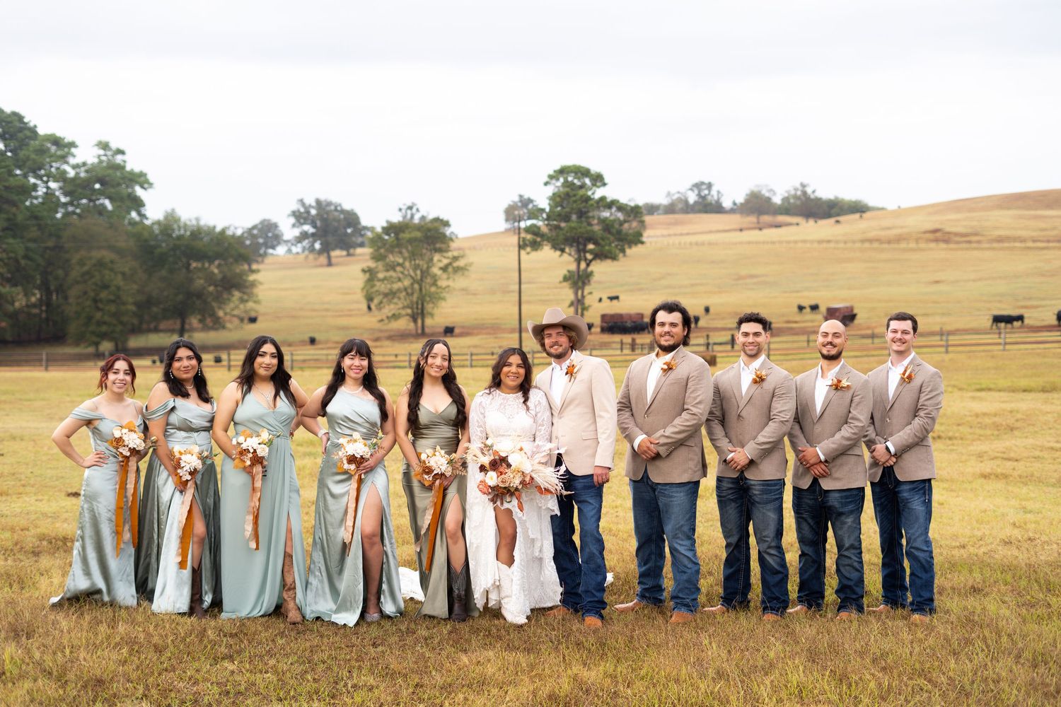 Full wedding party lined up outdoors against a scenic countryside backdrop.
