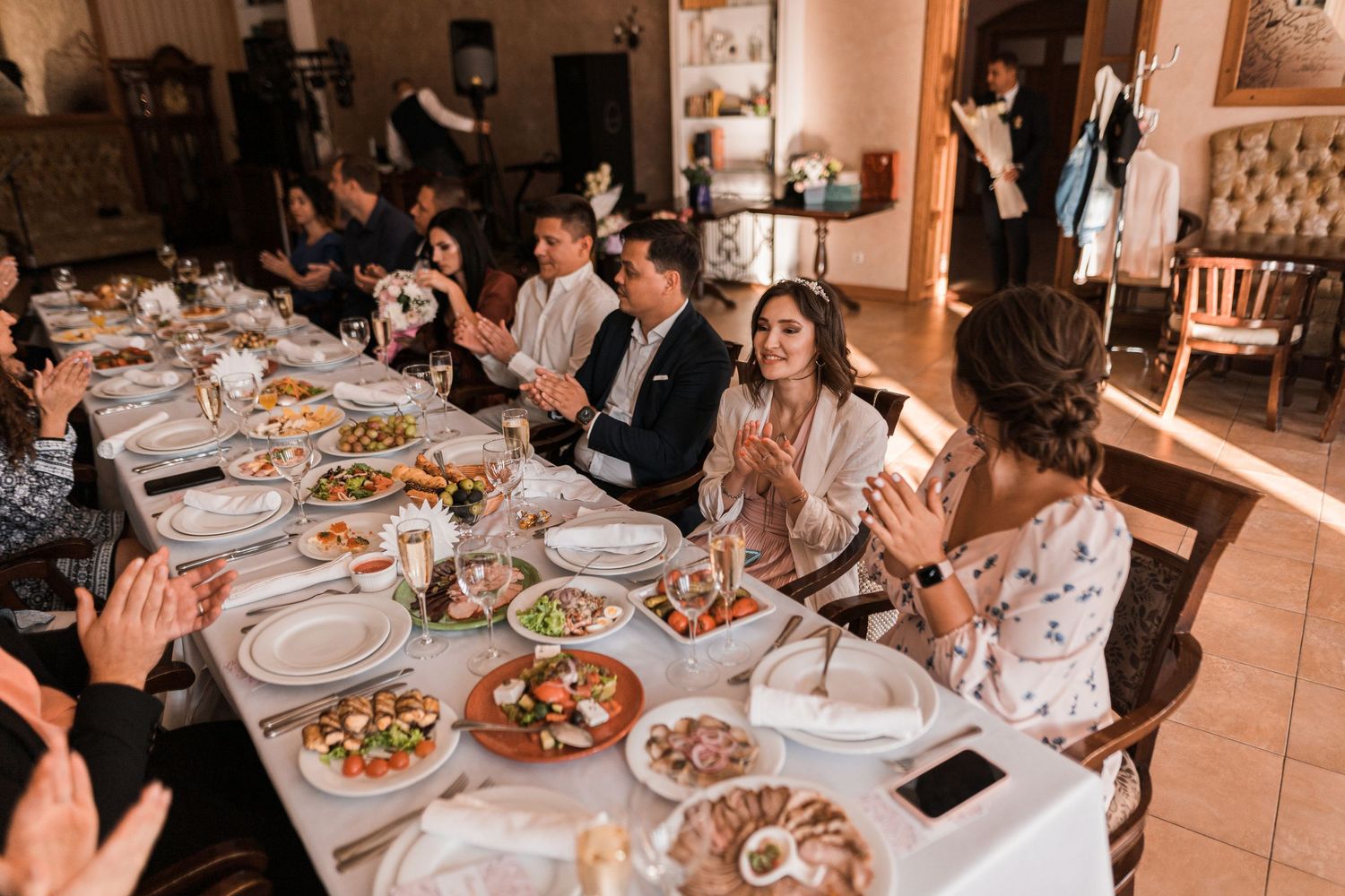 A group of people gathered around a long dining table enjoying a meal at a rustic restaurant venue.