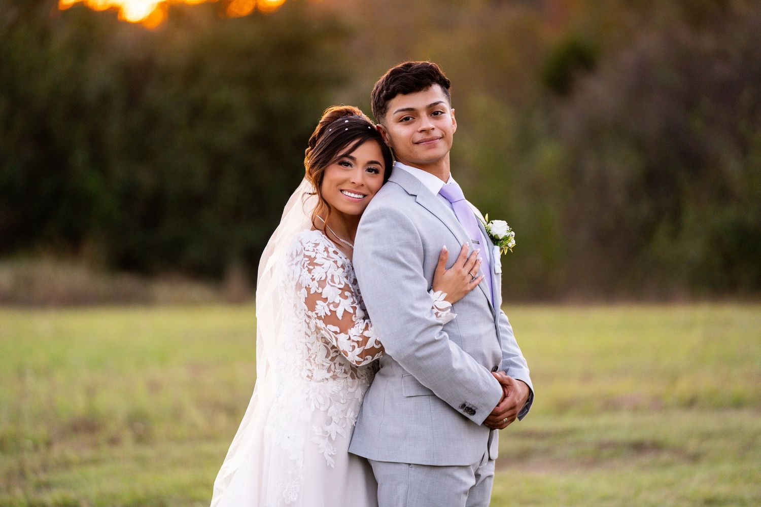 Romantic sunset portrait of newlyweds in lace gown and grey suit.