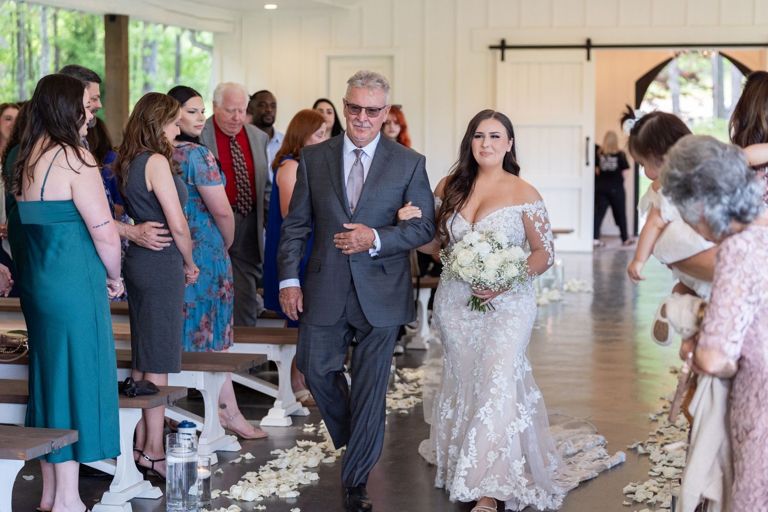 Wedding guests mingle and socialize during an elegant indoor reception with large windows and natural lighting.