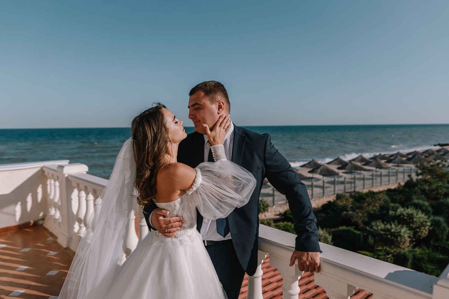 A romantic beach wedding photoshoot with couple embracing on sandy shores as waves crash behind them.