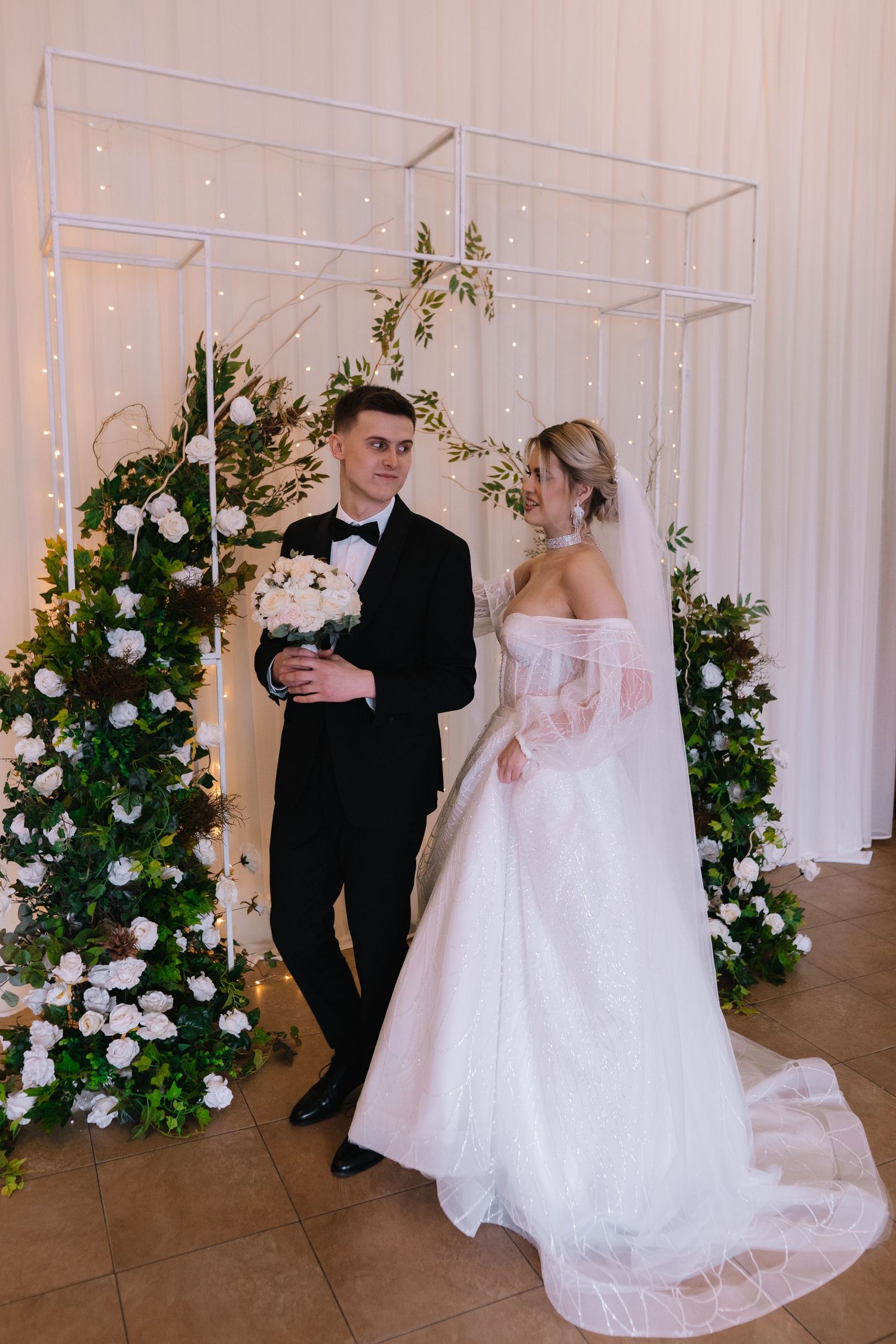 A series of wedding photos showing a couple in formal attire posing with floral arrangements and white drapes in the background.