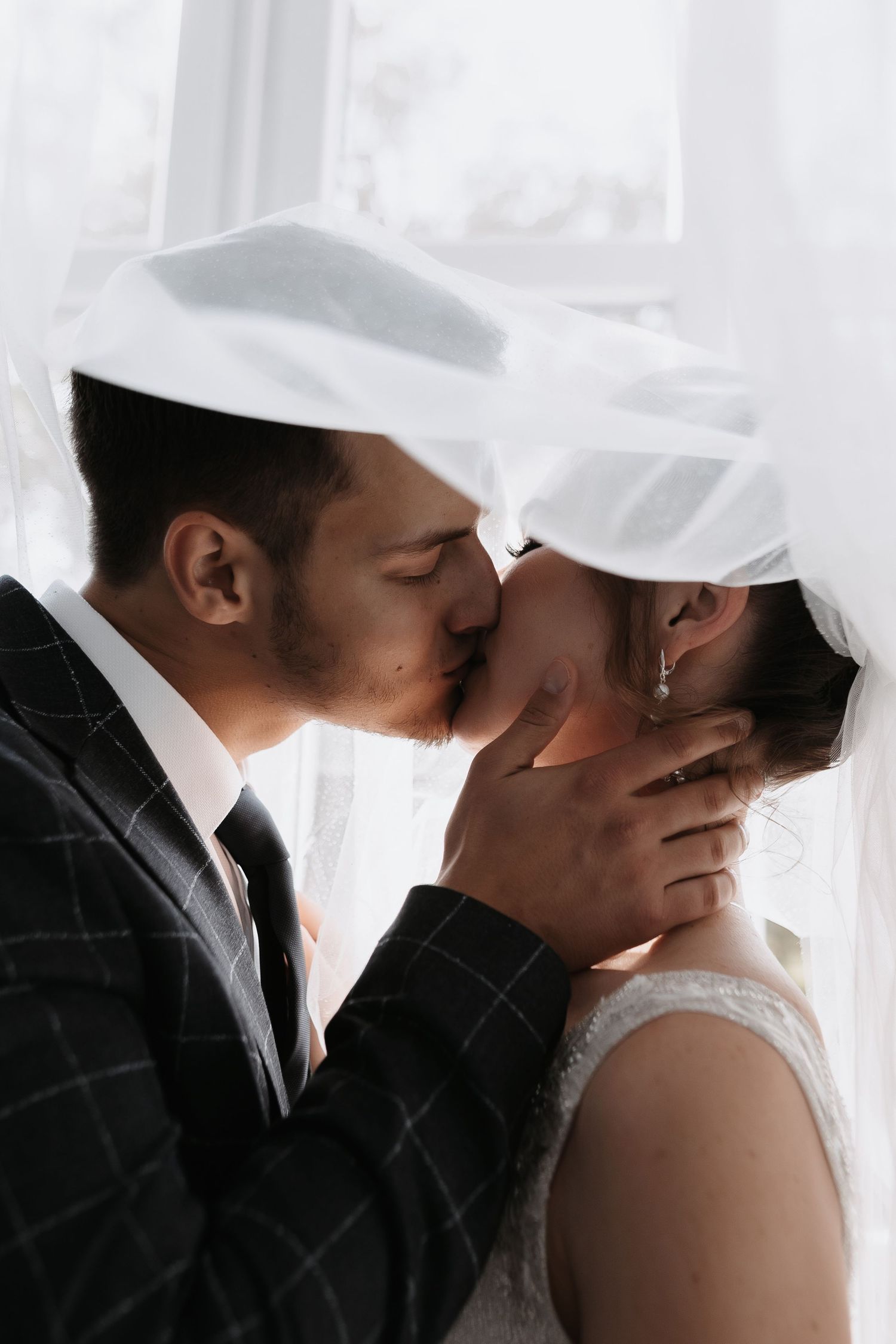 A romantic black and white photo series showing a couple sharing tender kisses during their wedding day.
