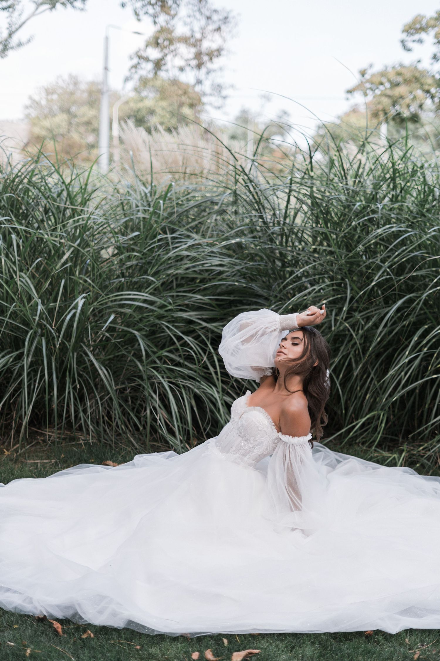 A flowing white wedding dress billows dramatically against tall green reeds in a dreamy outdoor photoshoot sequence.