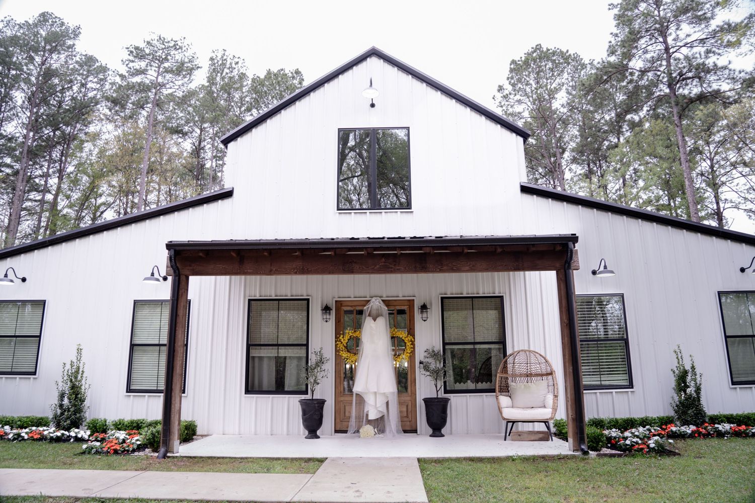 White church building with multiple connected sections and windows set among pine trees in a rural setting.