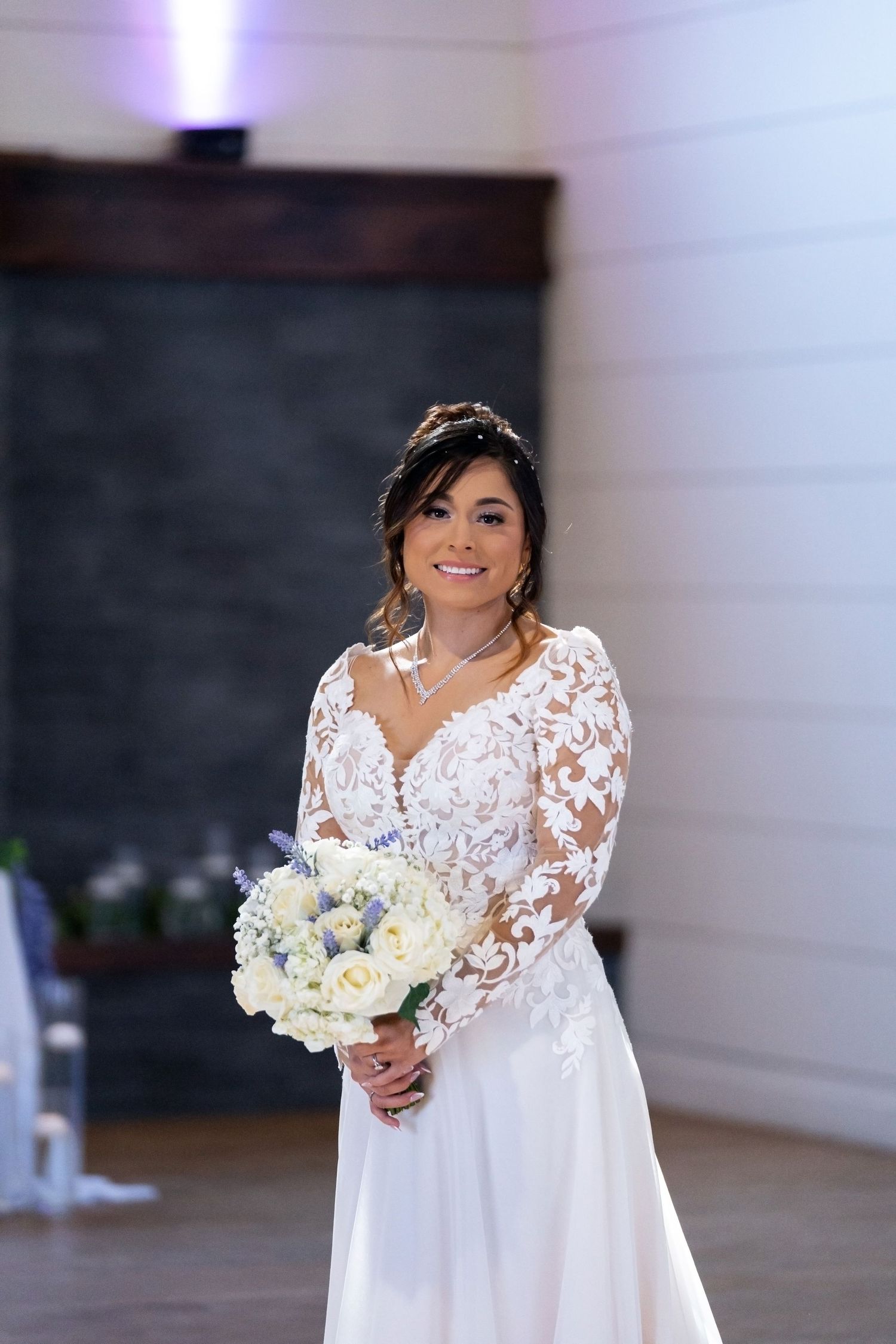 Beautiful wedding portrait featuring bride in lace sleeve gown holding white floral bouquet.