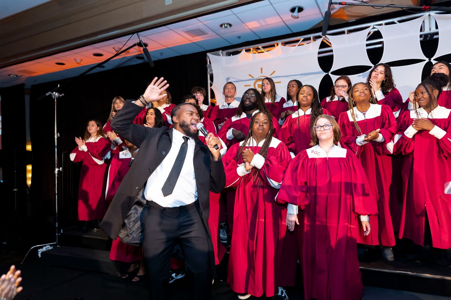 Choir members in bright red robes perform on stage during a concert.
