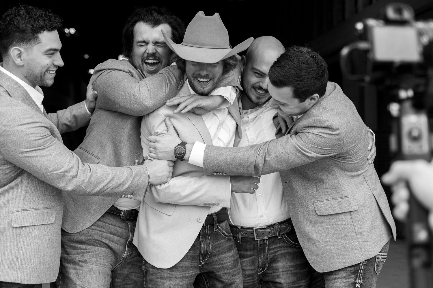 Groomsmen in matching gray suits and jeans share laughs during wedding party photos.