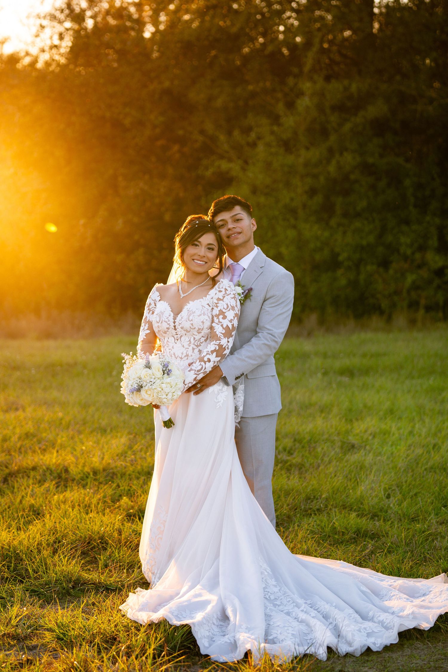 Romantic sunset wedding photos in field with couple in white dress and grey suit.