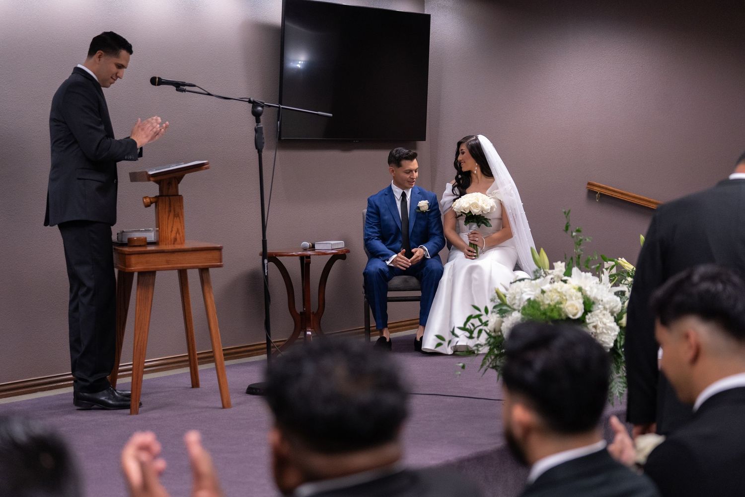 A wedding ceremony takes place in a church with people gathered to witness the couple exchanging vows.
