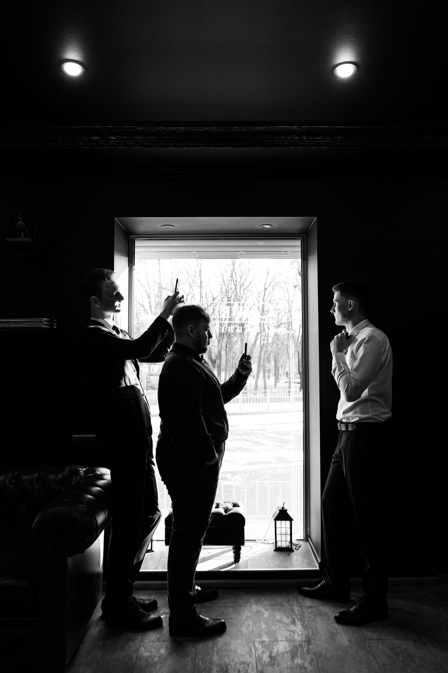 Silhouettes of people gathered in a doorway with bright backlighting creating dramatic contrast in black and white.
