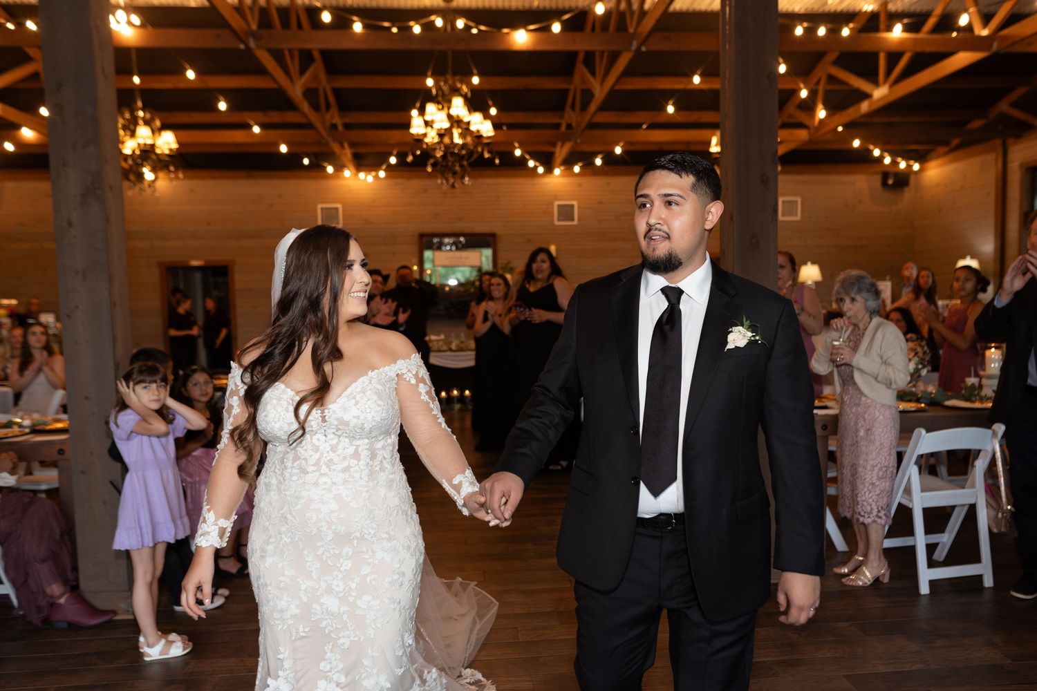 Wedding guests dance and celebrate on a warmly lit indoor dance floor during an evening reception.