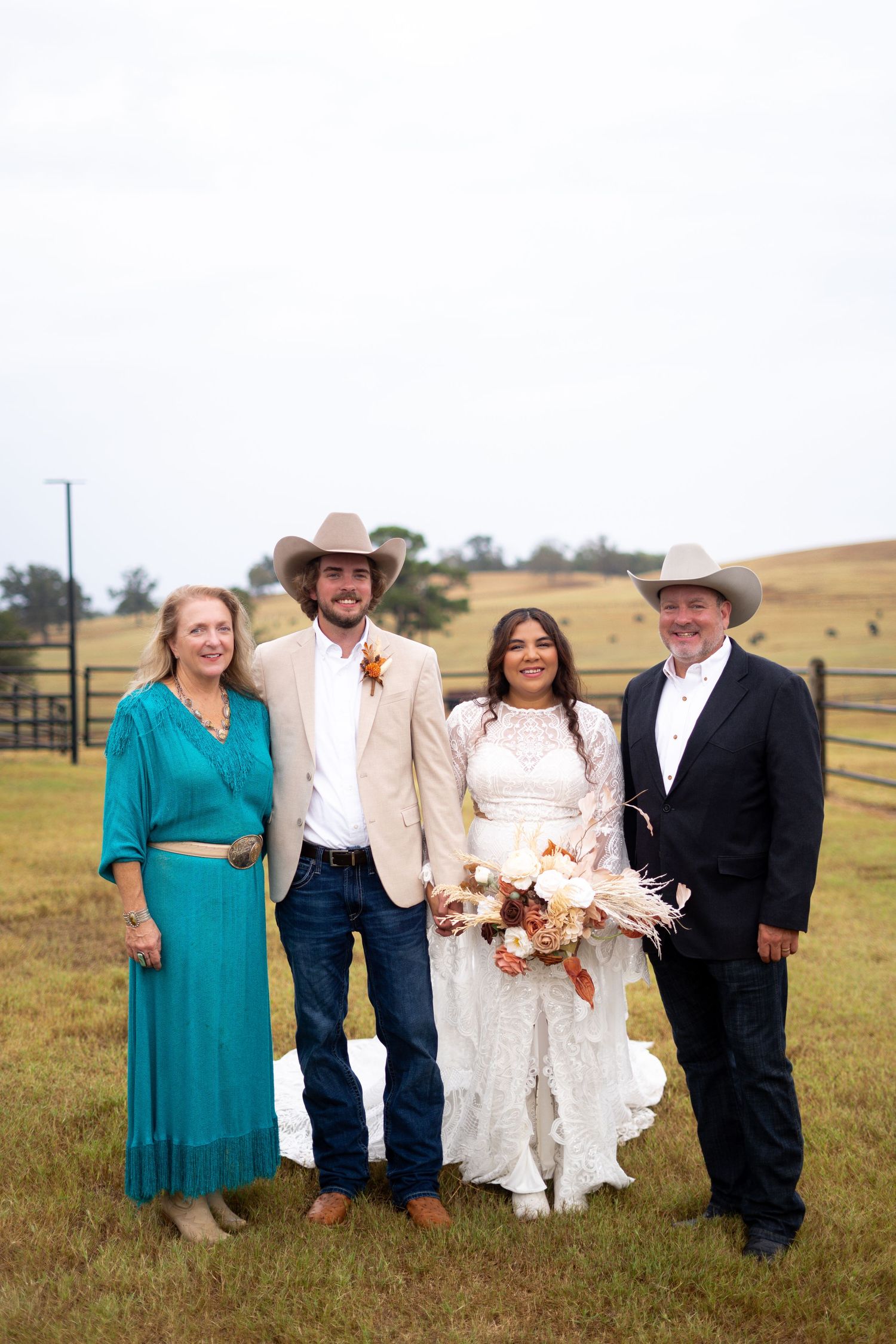 A wedding party poses together on a rustic ranch with rolling hills in the background.