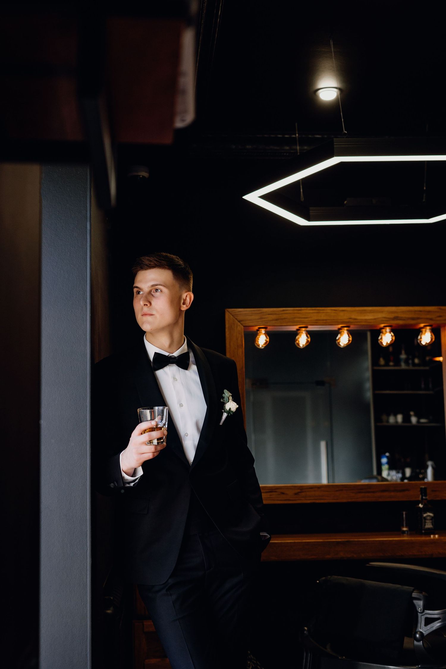 A moody portrait in a dimly lit bar with dramatic lighting and black suit attire.