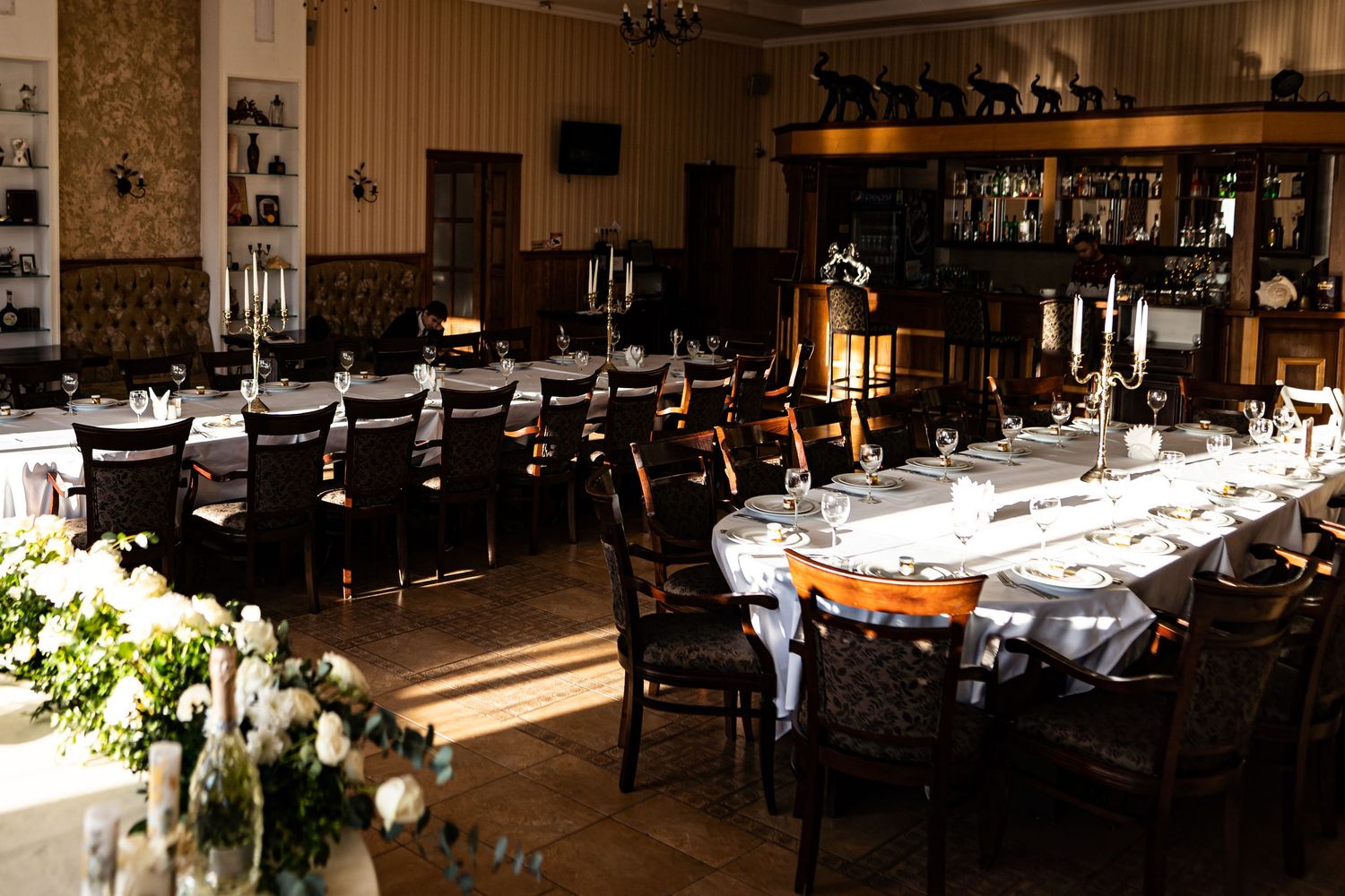 Elegant banquet hall with white tablecloths and dark wood accents illuminated by warm lighting for an upscale event.