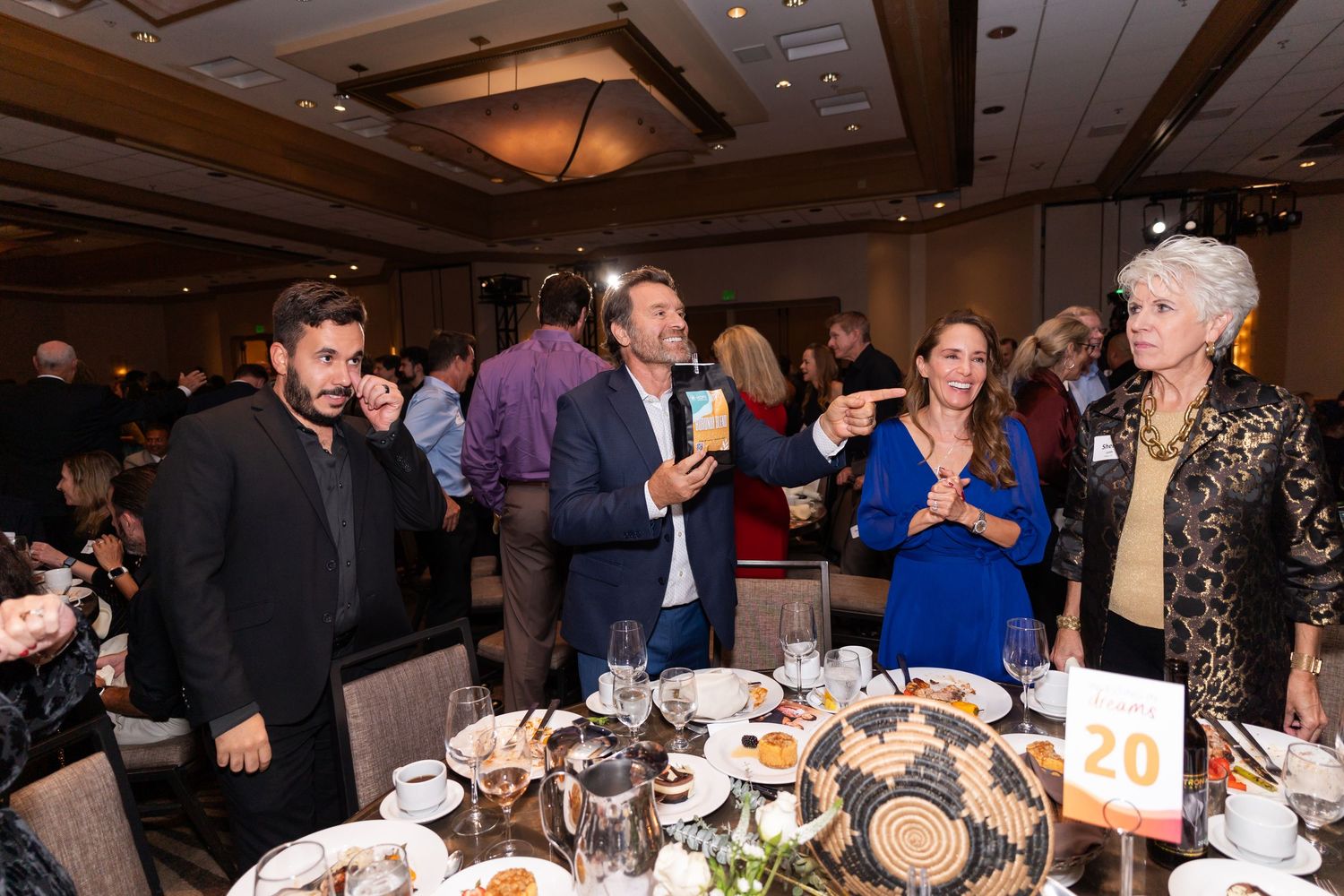 Guests mingling and socializing around dining tables at formal event.