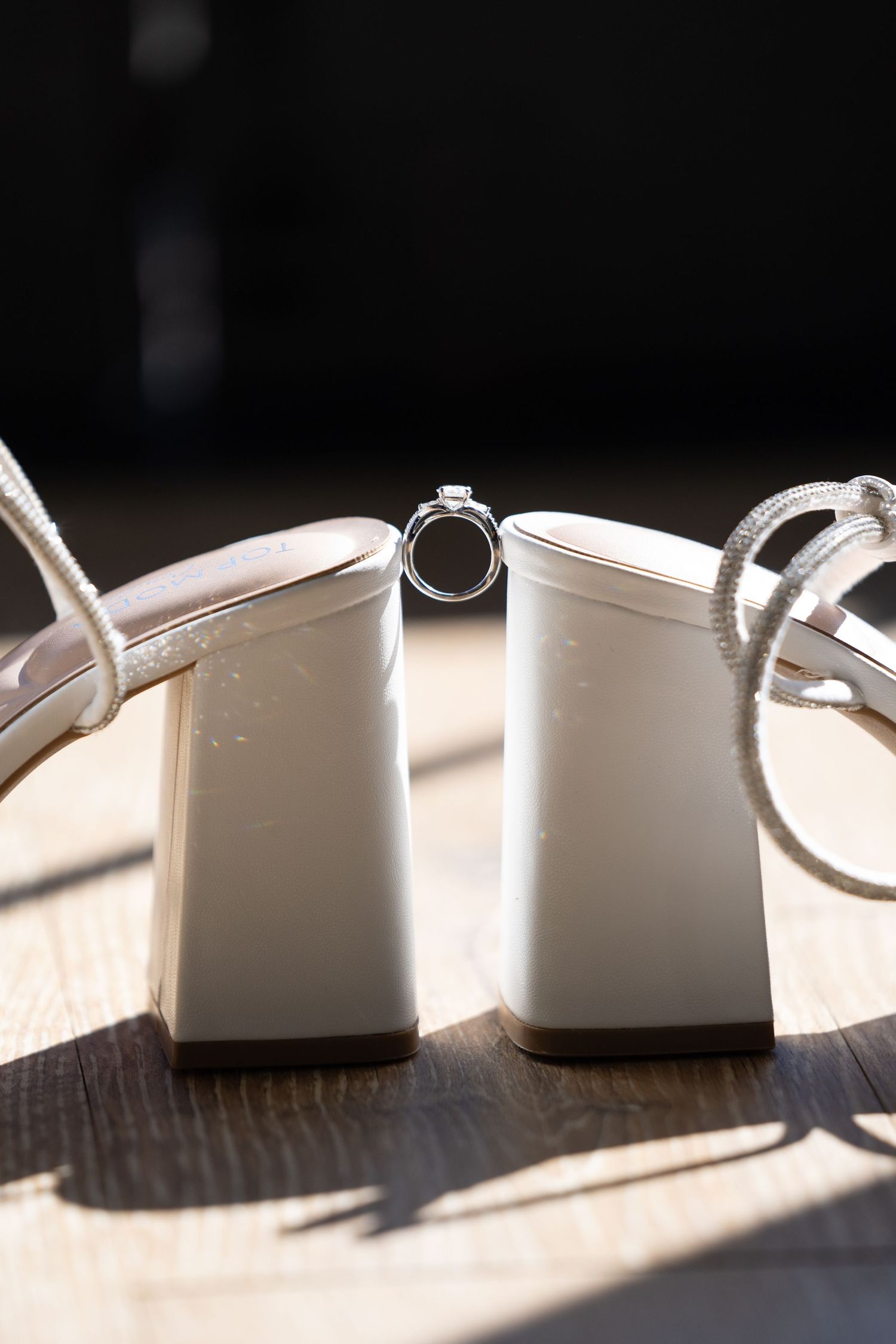 Wedding rings casting dramatic shadows on a white surface in natural lighting.